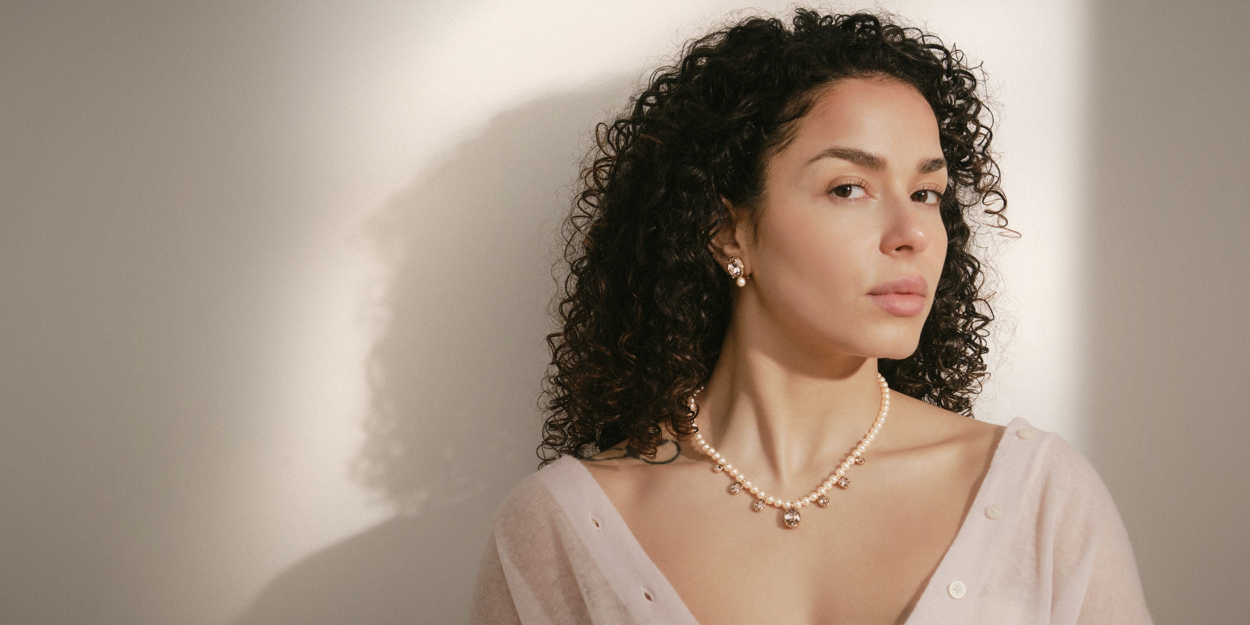 Woman wearing a pearl necklace against a plain background