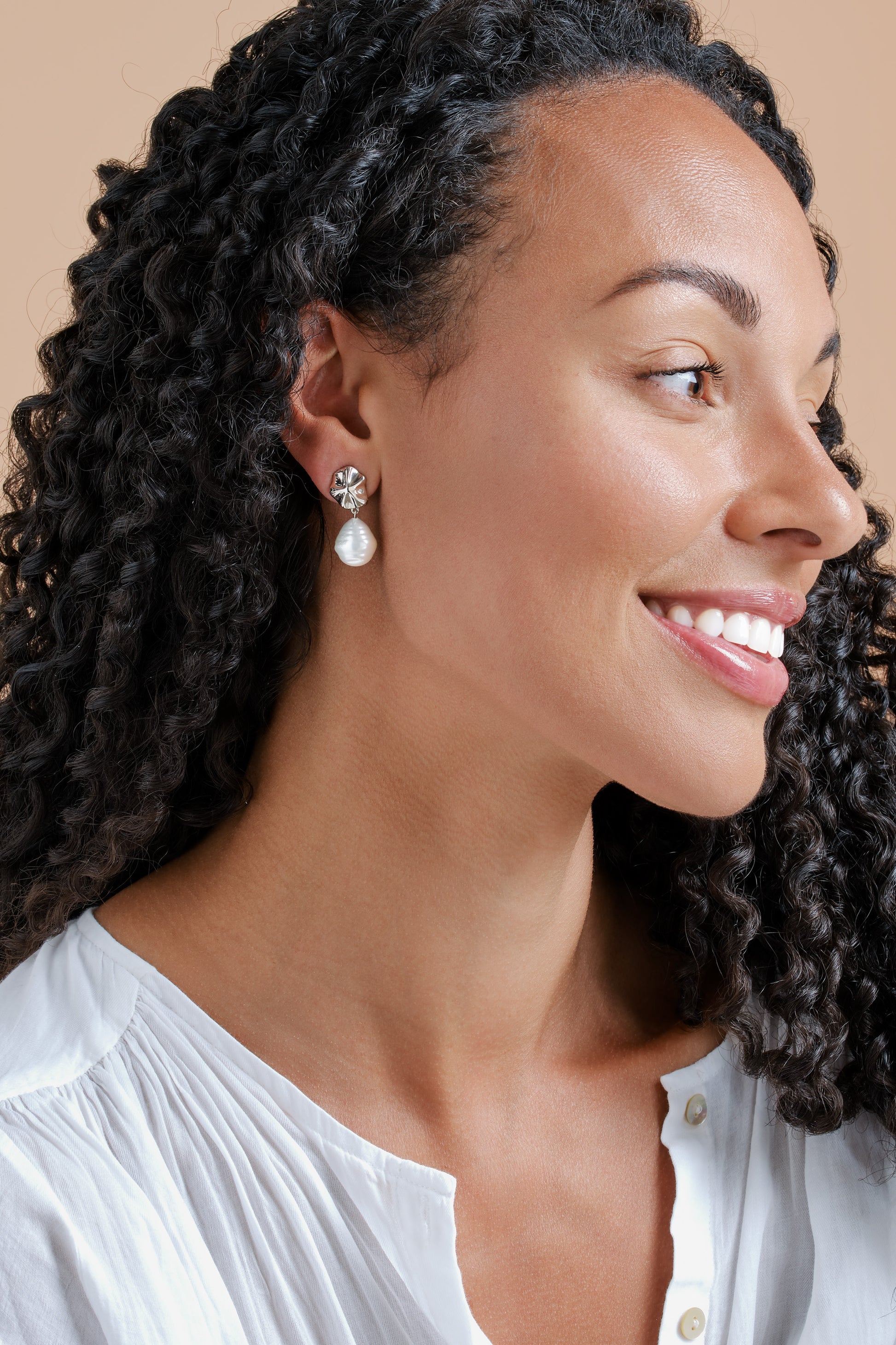 A model wearing platinum shell and baroque pearl clip earrings