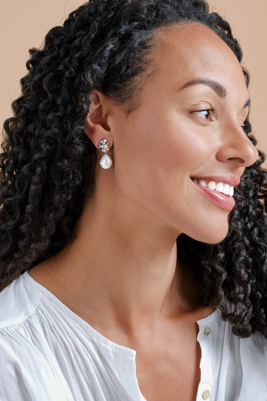 A model wearing platinum shell and baroque pearl clip earrings