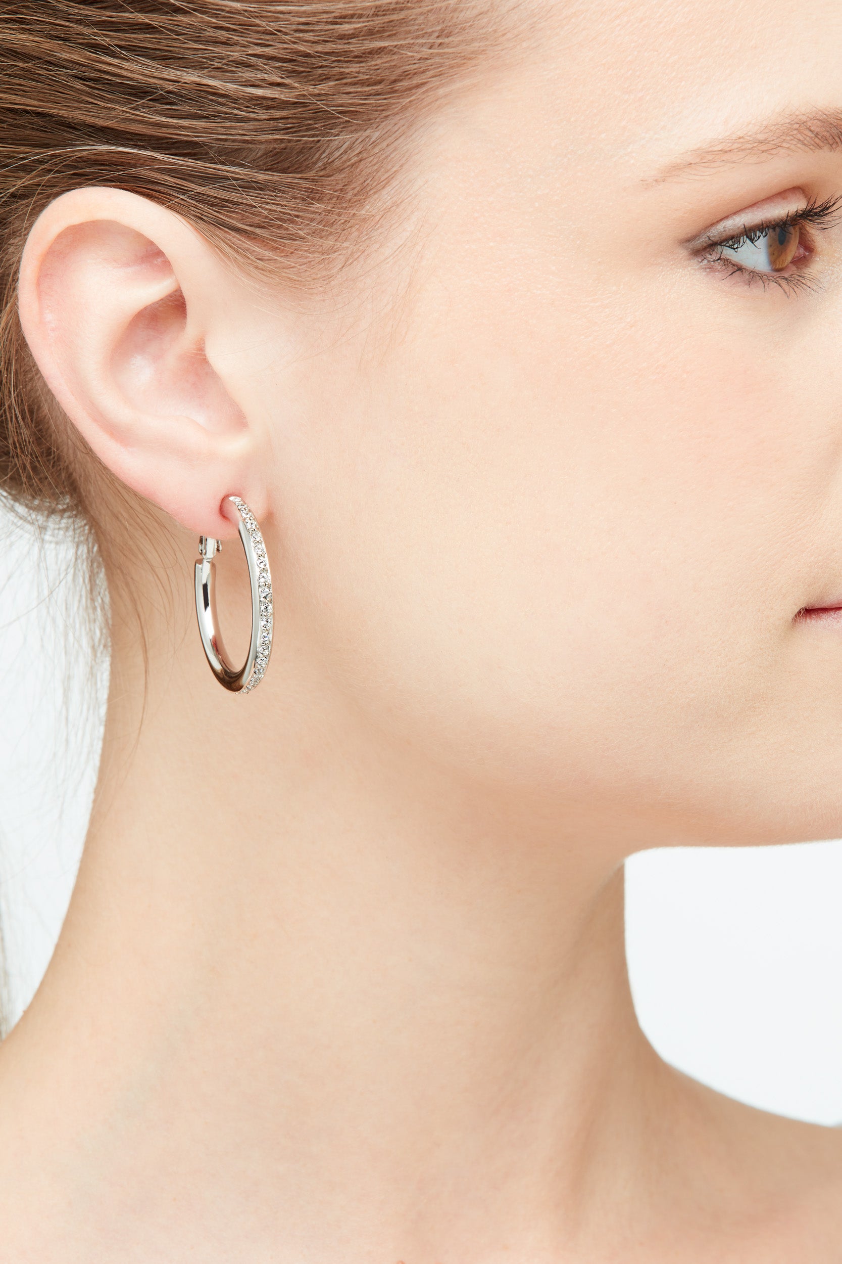 A close up shot of Emma Holland crystal hoop earrings with clip on fastening