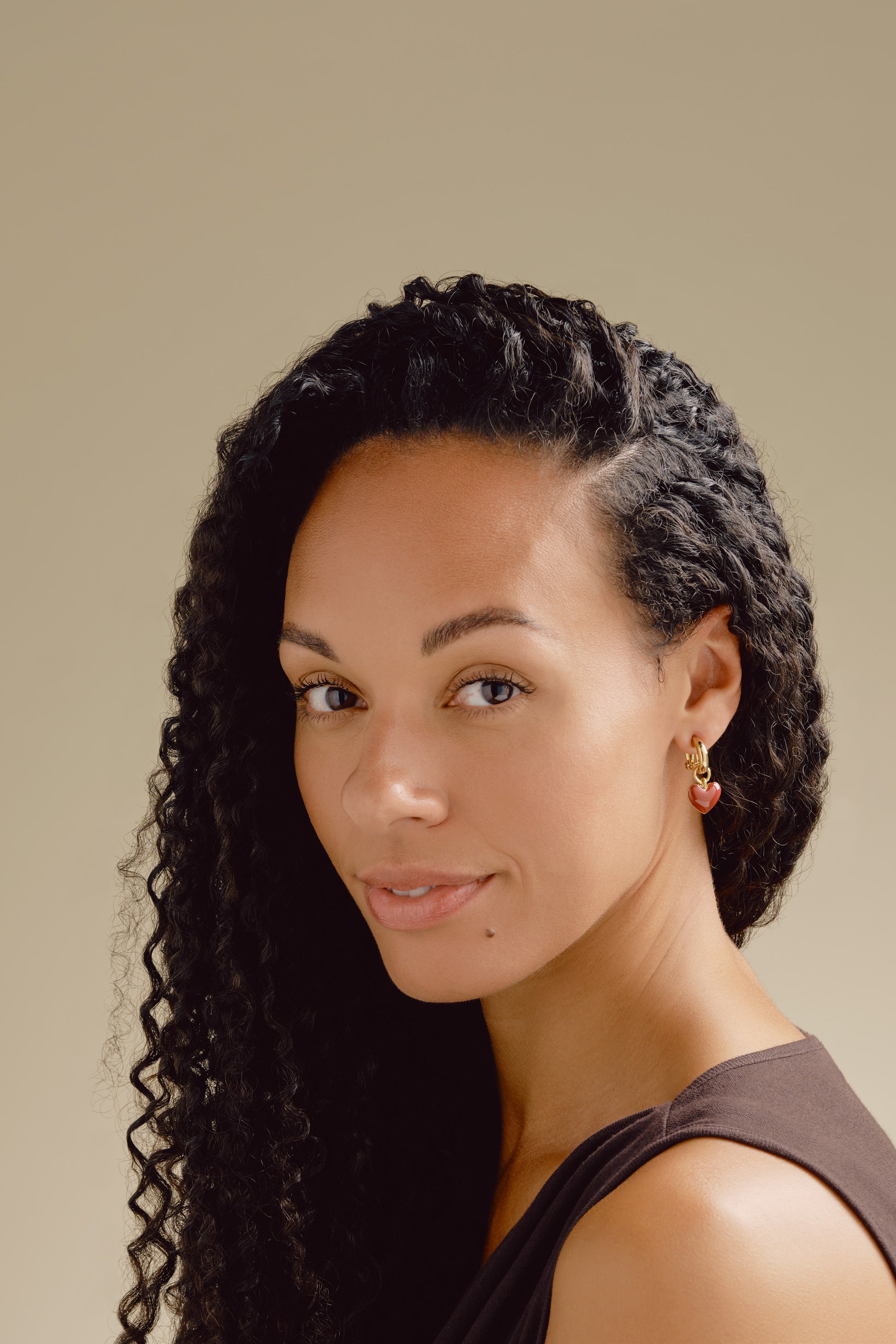 A model wearing red heart and gold hoop clip on earrings