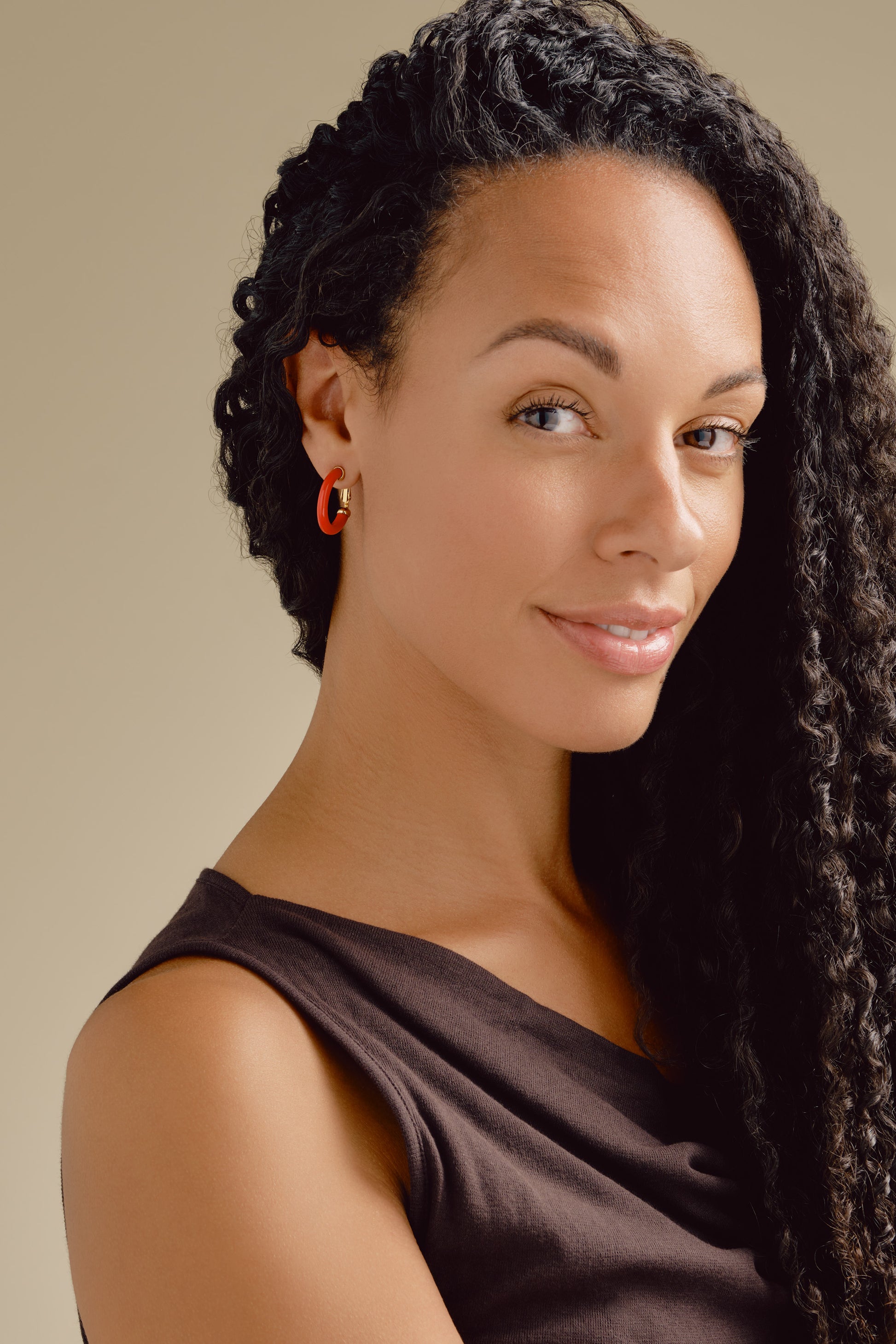 A model wearing red resin hoop earrings