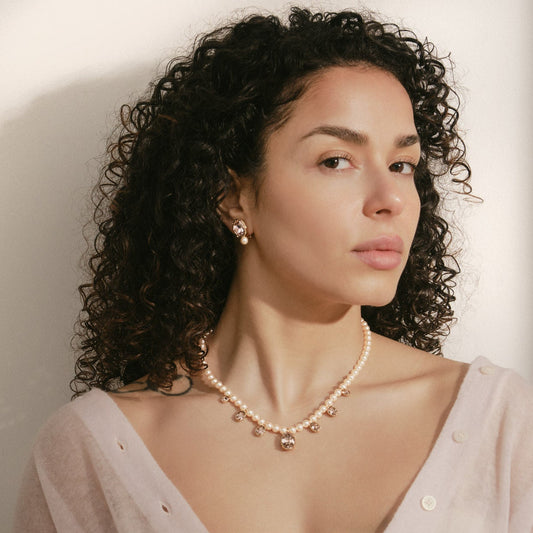 Woman wearing a pearl necklace against a plain background
