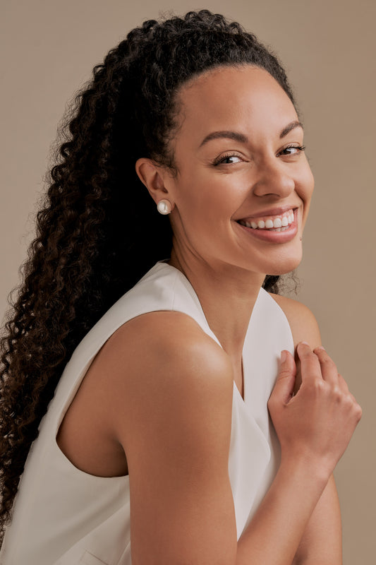 A model wearing large pearl clip on earrings