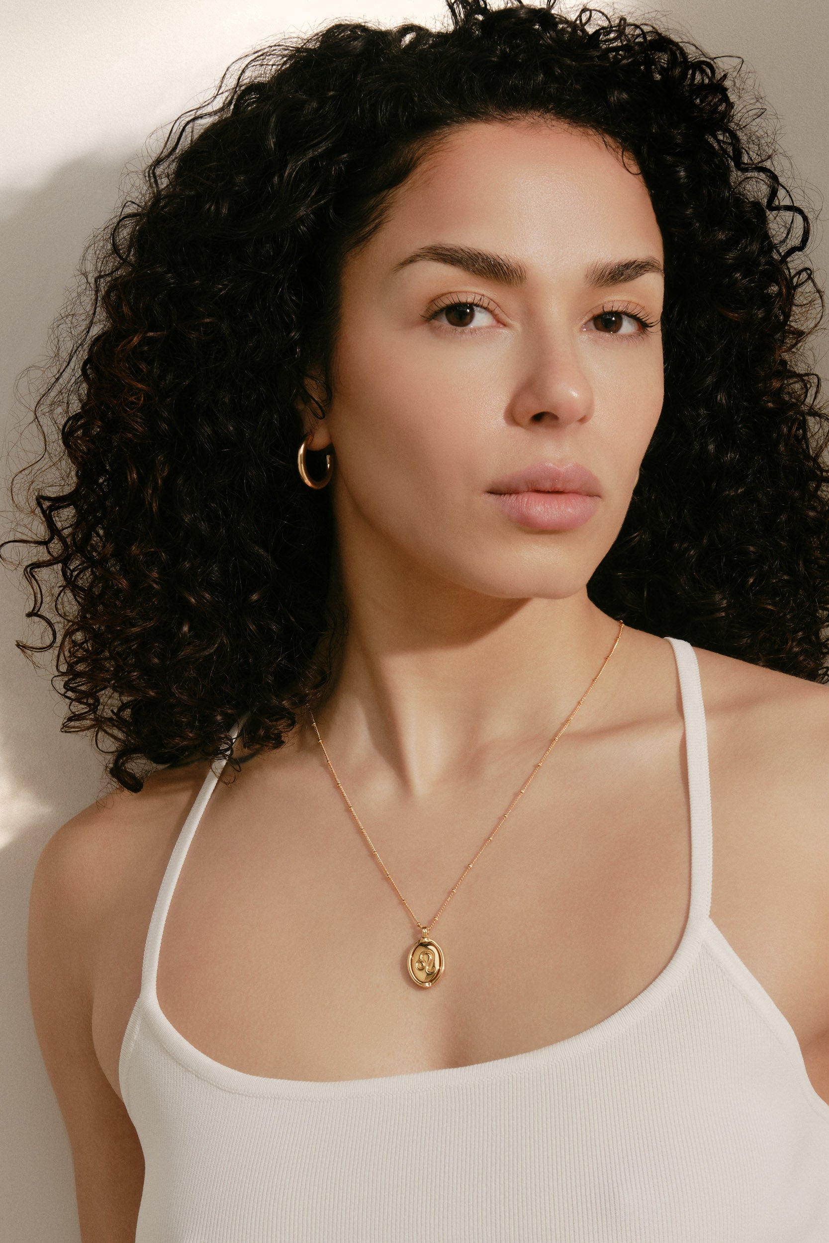 Woman wearing a gold necklace with a plain background